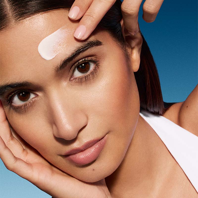 uma mulher aplicando protetor solar