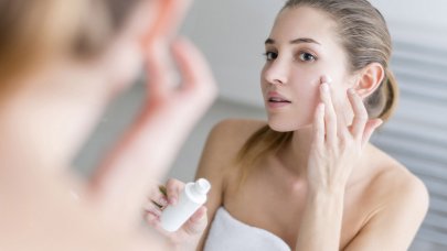 Woman applying cream on her face in a bathroom